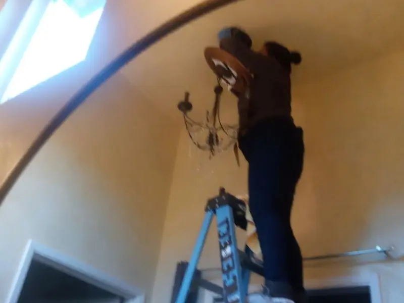 Electrician installing a chandelier in a Cleveland residence